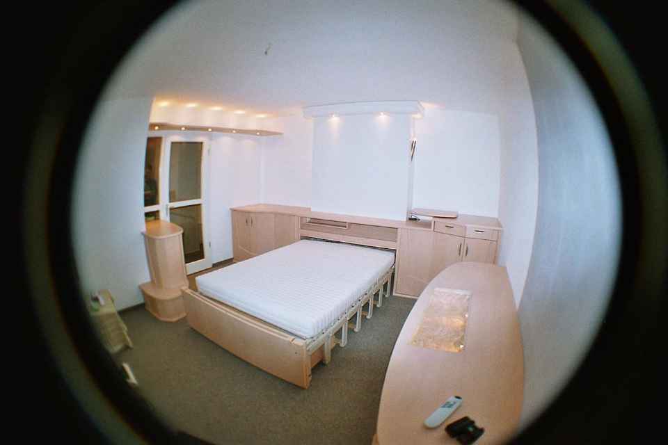 Zu sehen ist ein Wohn-Schlaf-Arbeitszimmer-mit-Belitec-Bett-Sitz-Schrank